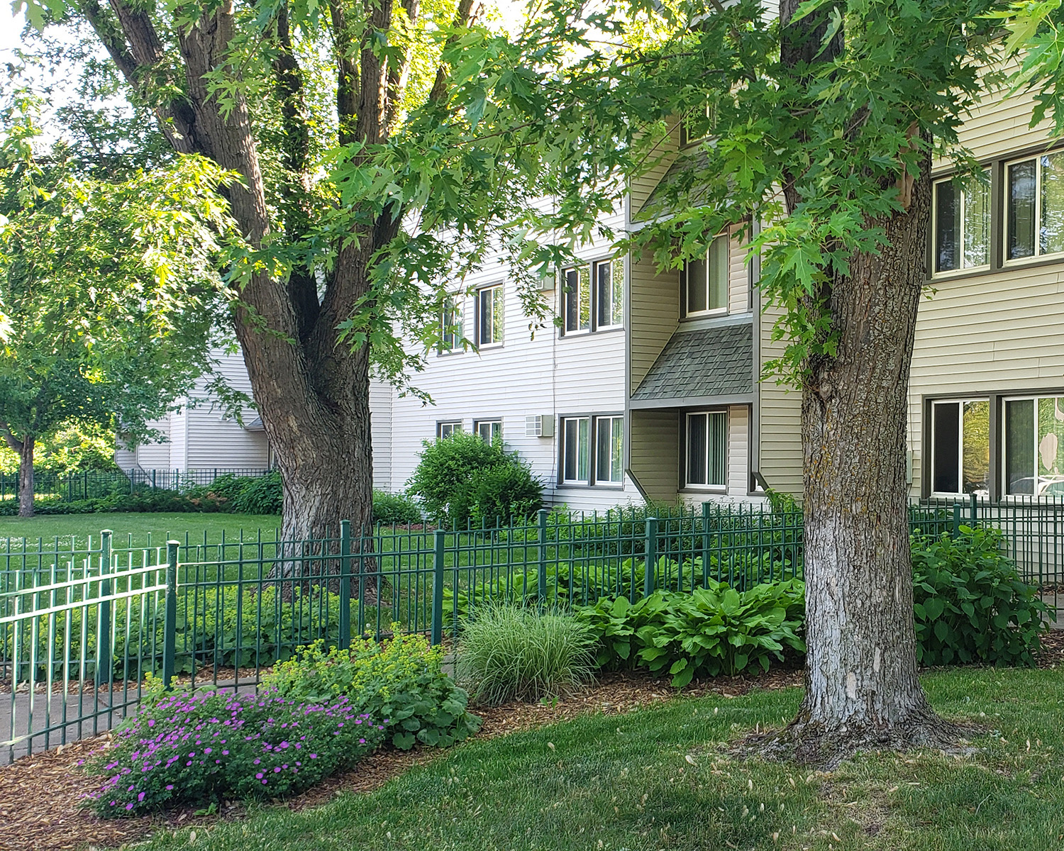 a white house with trees and flowers in front of it