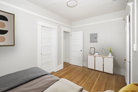 A bedroom with a bed, a dresser, and a painting on the wall.