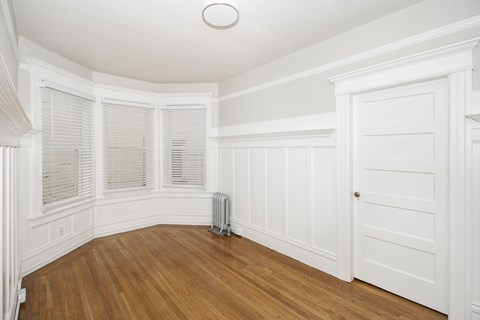 A room with white walls and wooden floors with a white door.