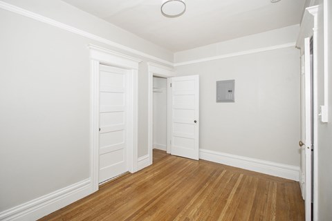 A room with white walls and wooden floors with two doors.