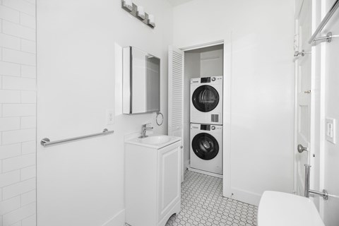 A white bathroom with a washer and dryer in the doorway.