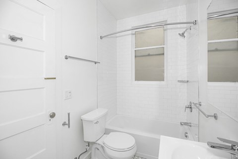 A white bathroom with a toilet, sink, and bathtub.
