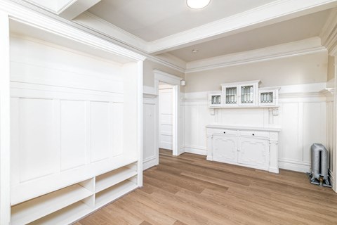 A white room with wooden floors and a fireplace.
