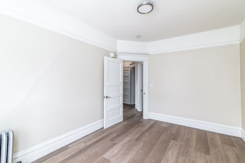 A room with a white door and a wooden floor.