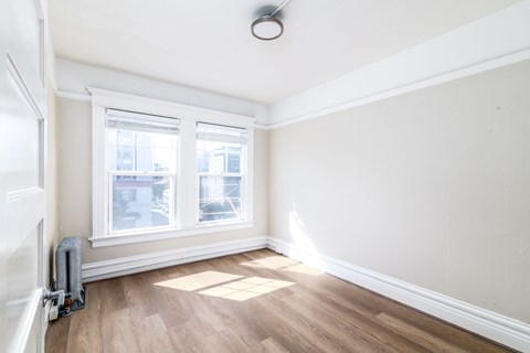 A room with a window and a wooden floor.