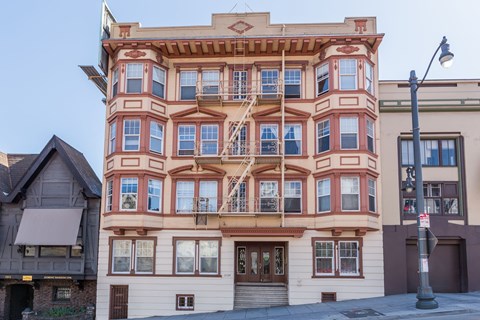 A tall building with many windows and balconies is seen in the image.