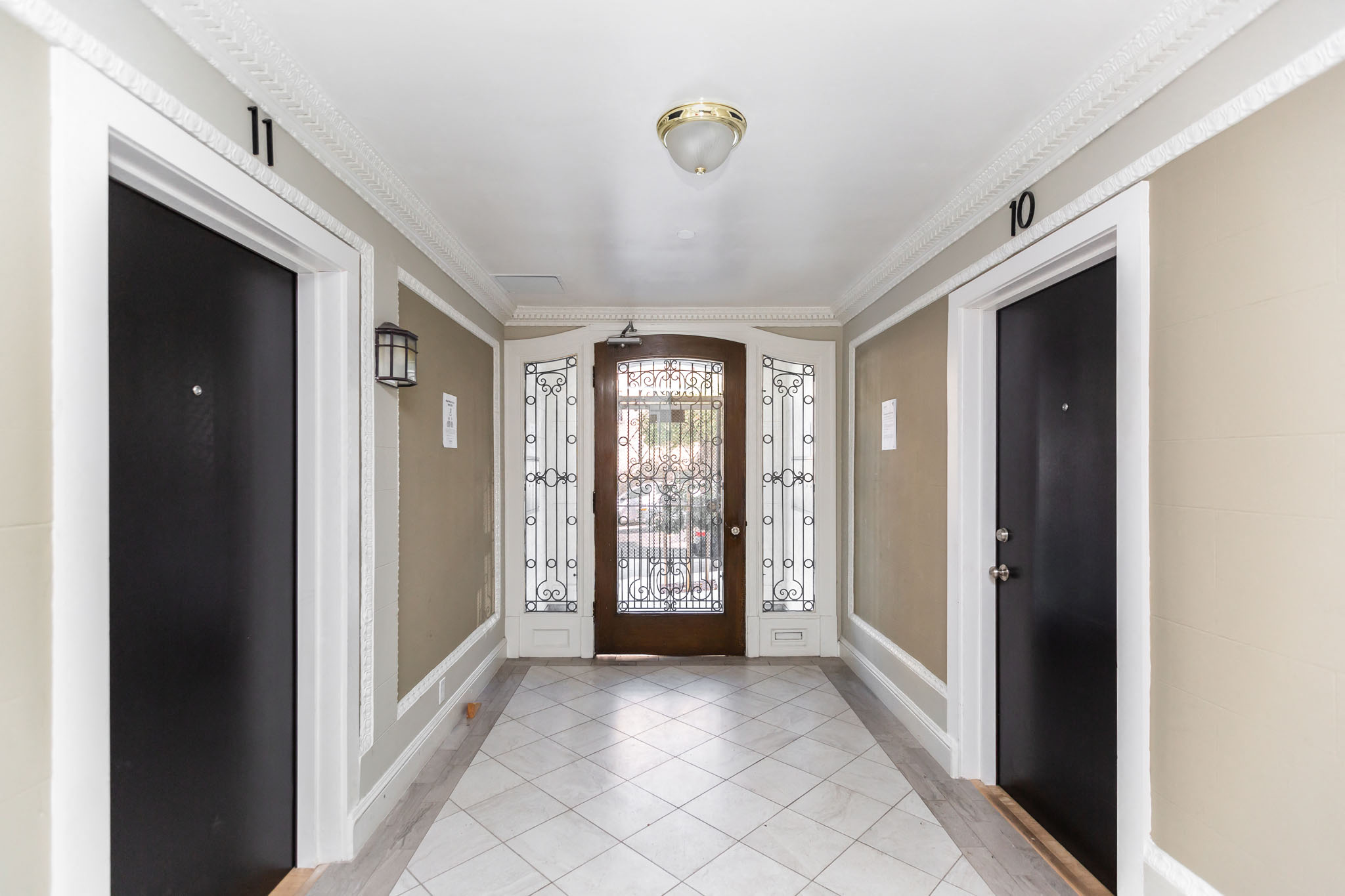 A hallway with black doors and a white tiled floor.