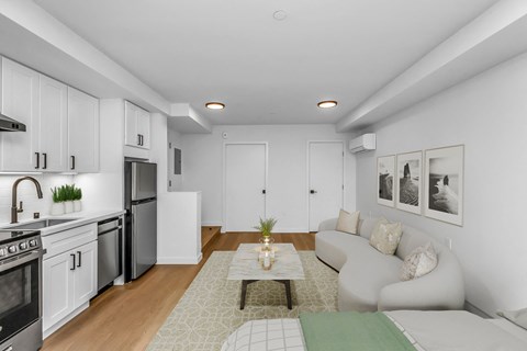 A modern kitchen with white cabinets and a dining area with a white couch.
