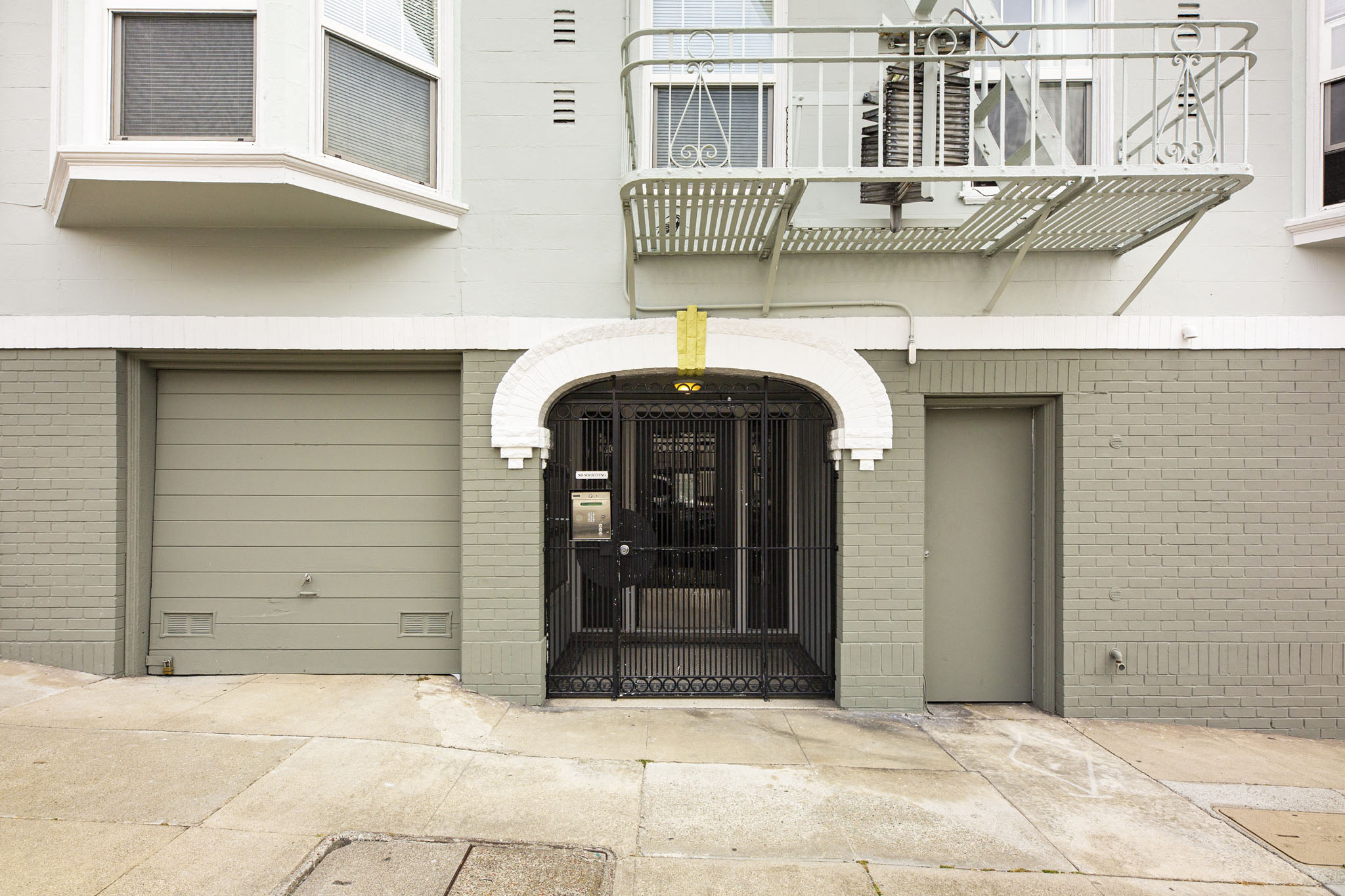A building with a black gate and a balcony with a metal railing.