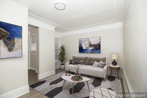 A living room with a white couch, a coffee table, and two paintings on the wall.