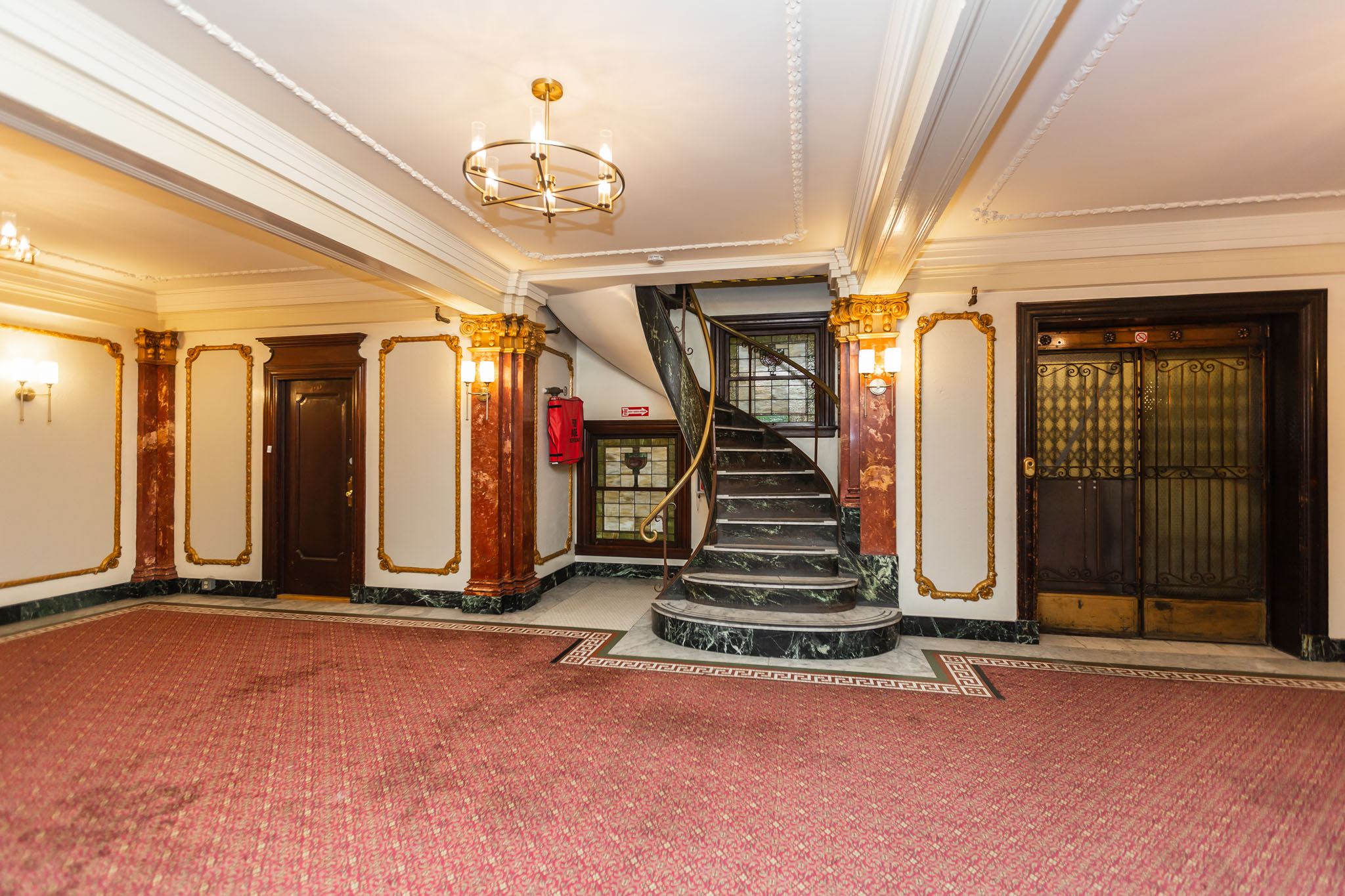 A grand staircase with a red carpeted floor and gold accents.