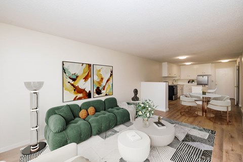 A living room with a green couch and a painting on the wall.
