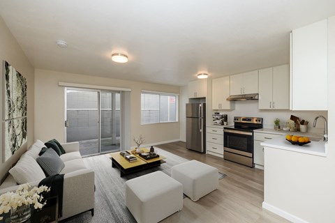 A modern kitchen and living room with a grey couch and a coffee table.