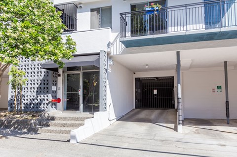 A white building with a black gate and a red sign on the wall.