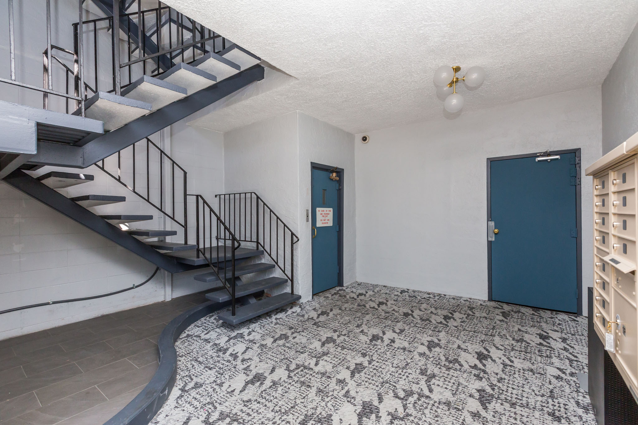 A room with a blue door and a staircase with a metal railing.