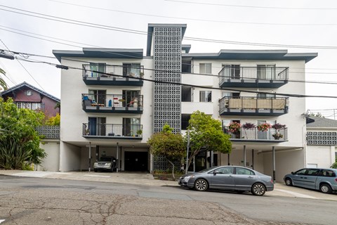 A modern apartment building with a car parked in front.