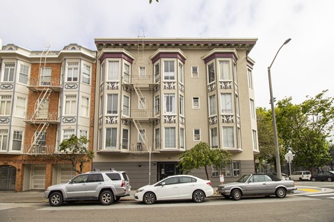 A row of cars are parked in front of a building.
