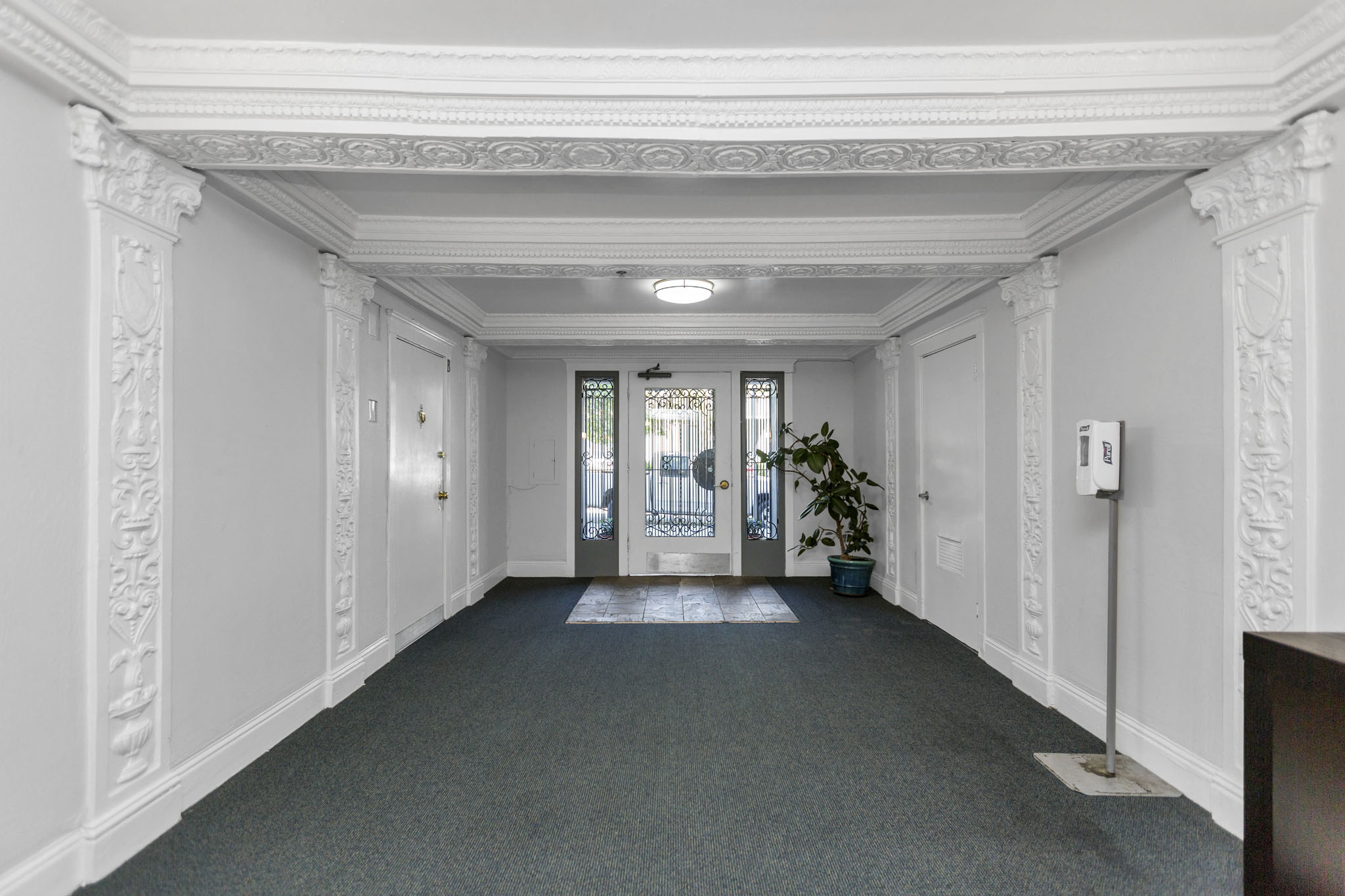 A hallway with white walls and a grey carpet.