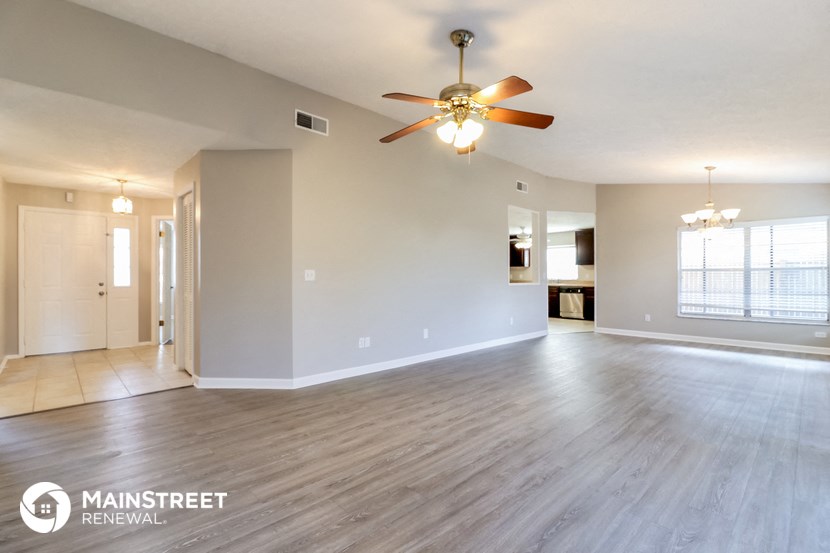 the living room and dining room of an empty house with a ceiling fan