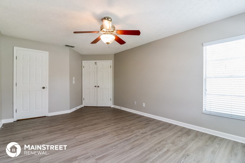 the spacious living room with a ceiling fan