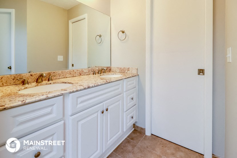 a bathroom with white cabinets and marble counter tops