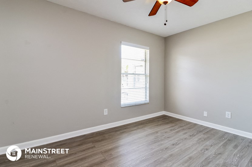 the spacious living room with wood flooring and a ceiling fan