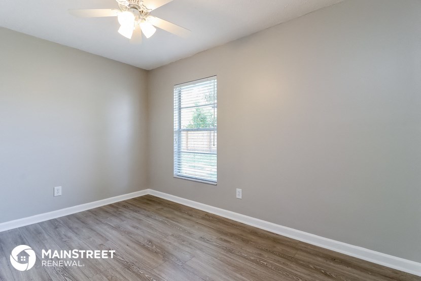 the spacious living room with wood flooring and a window