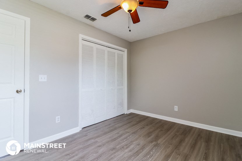 an empty living room with a ceiling fan and a closet