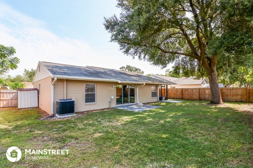 a small tan house with a yard and a tree