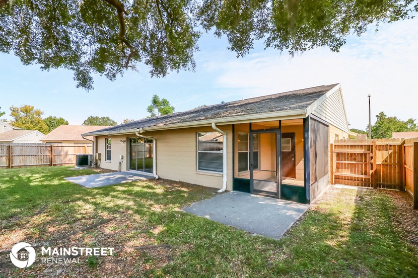 a small tan house with a yard and a wooden fence