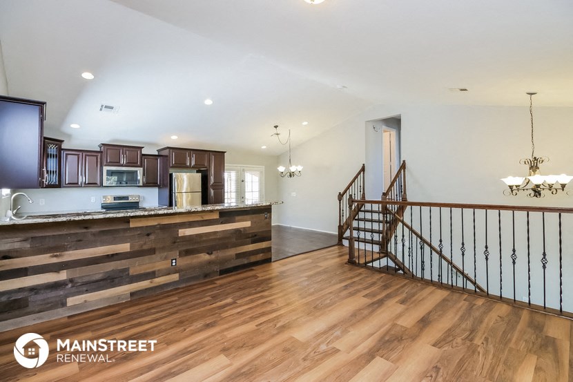 an open kitchen and living room with wood floors and a staircase