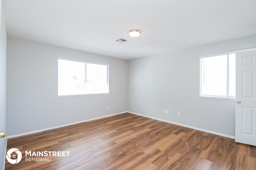 the spacious living room with hardwood flooring and two windows