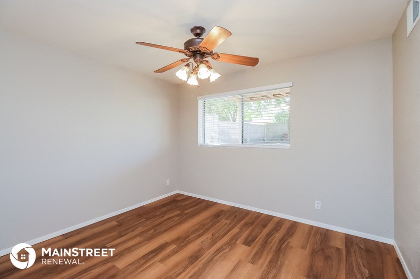 the spacious living room with wood flooring and a ceiling fan