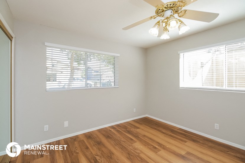 the spacious living room with hardwood flooring and a ceiling fan