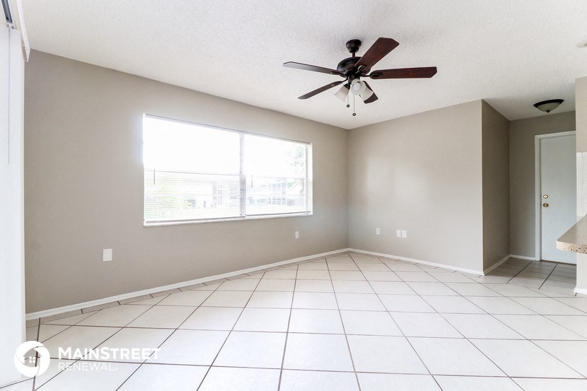 an empty living room with a ceiling fan