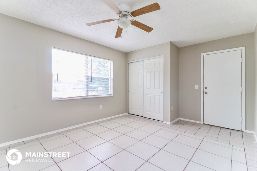 an empty living room with a ceiling fan and a window
