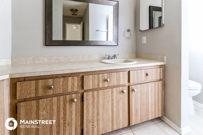 a bathroom with wooden cabinets and a sink and a mirror