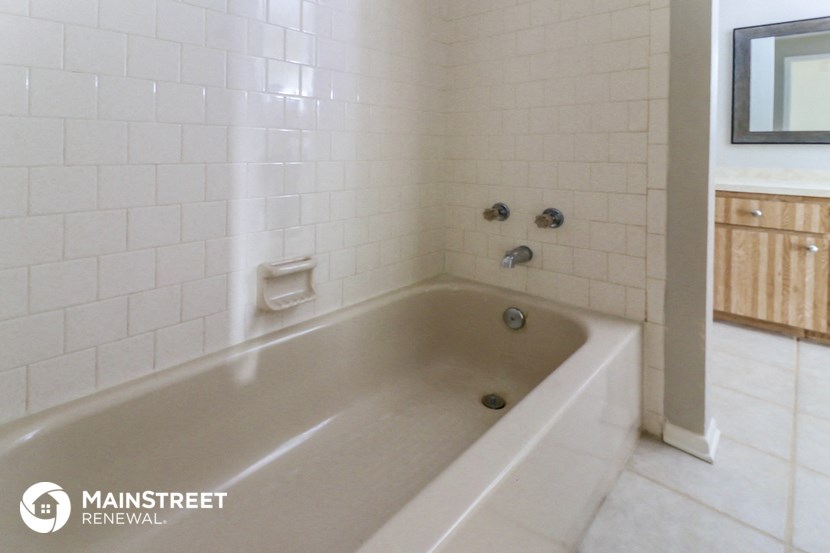 a white bath tub in a white tiled bathroom