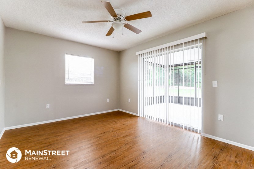 an empty living room with wood floors and a ceiling fan