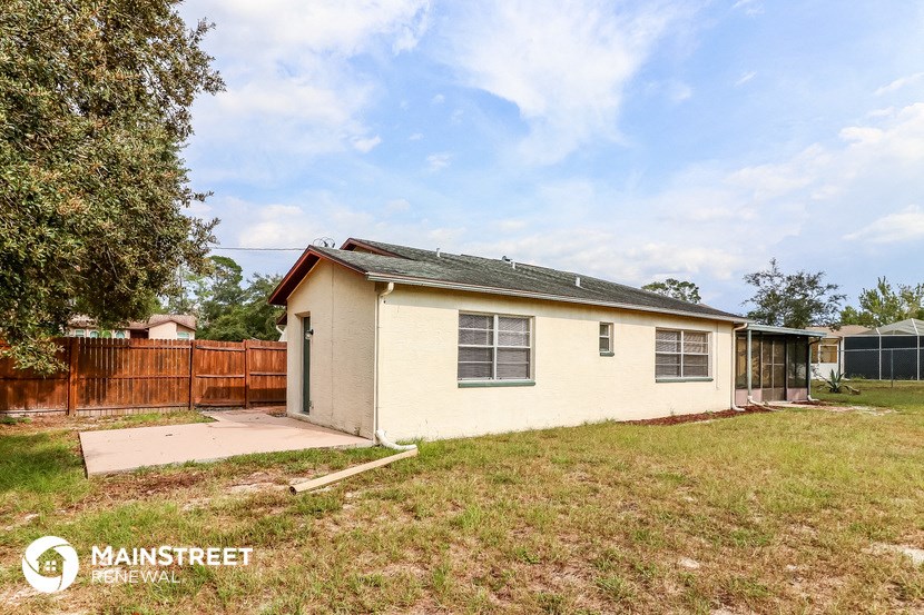 a small yellow house with a yard and a fence