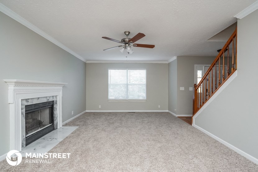 a living room with a fireplace and a ceiling fan