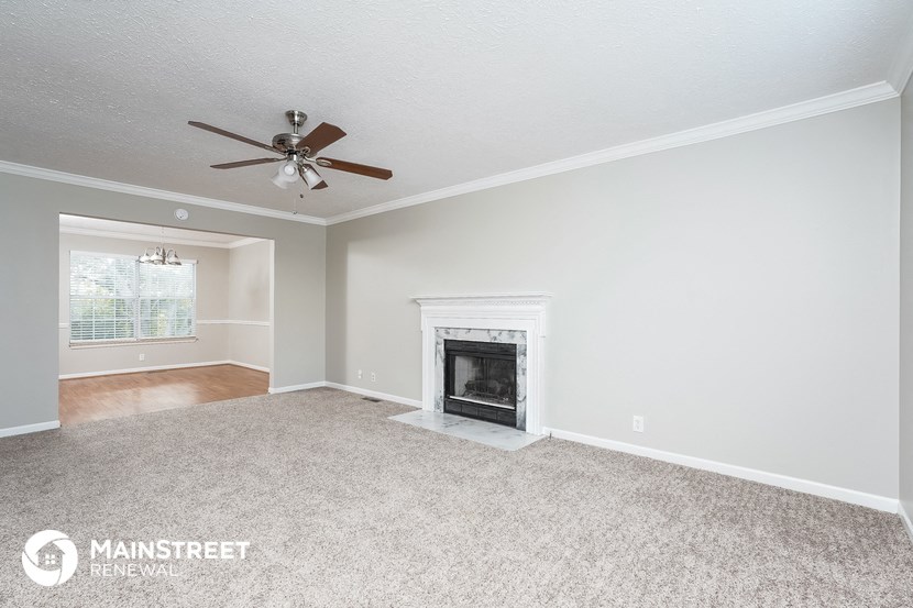 a living room with a fireplace and a ceiling fan