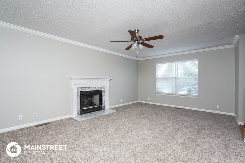 the living room has a fireplace and a ceiling fan