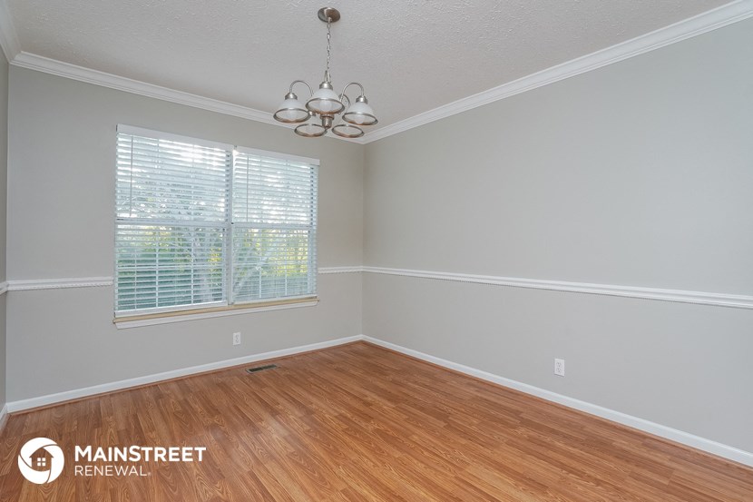 the living room of a home with wood floors and a window