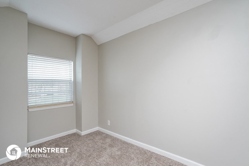 the upstairs bedroom has a large window and carpeted flooring