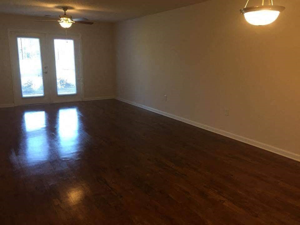 an empty living room with wooden floors and a ceiling fan