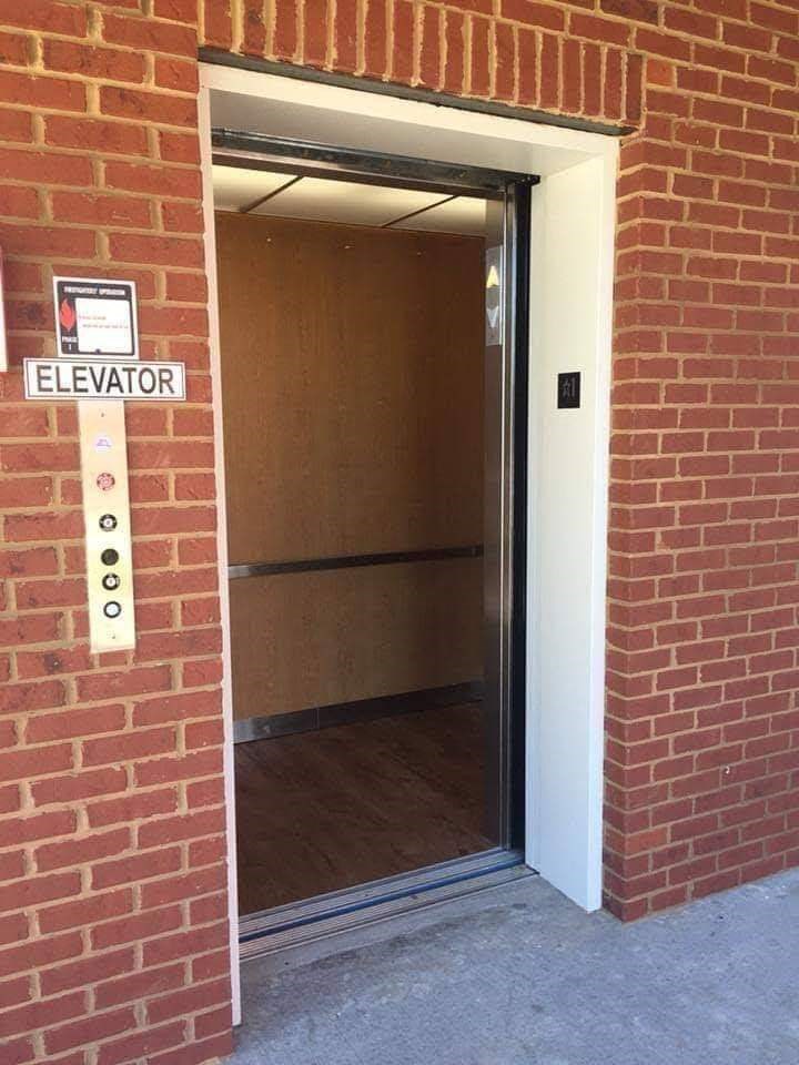 a brick wall with an open door to an elevator