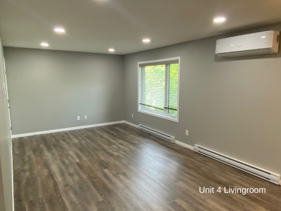the living room of a new home with wooden floors and a window