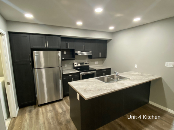 an updated kitchen with stainless steel appliances and marble counter tops