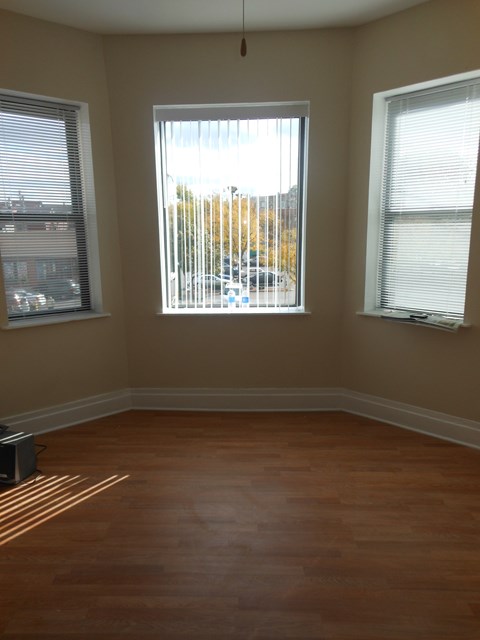 an empty room with three windows and a wood floor